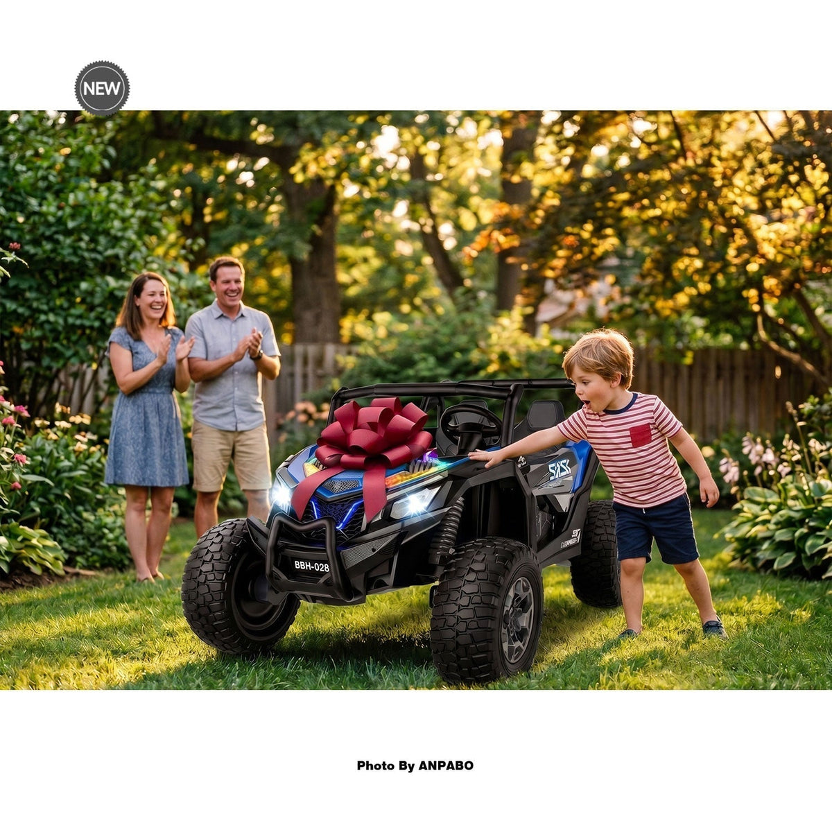 A surprised boy touching a blue kids 24V ride-on car with a large red bow during a backyard birthday reveal.